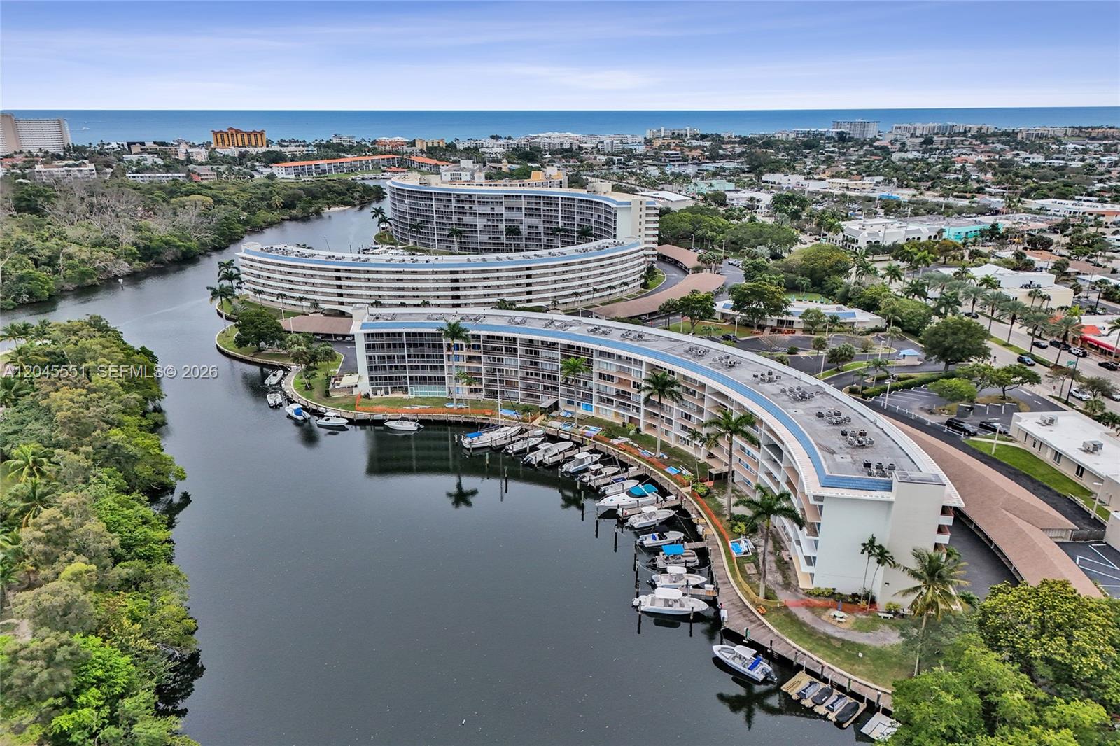 Aerial view of curved residential buildings along a canal with docked boats — 1301 E Hillsboro Blvd # 307, Deerfield Beach FL 33441, DEERFIELD BEACH, FL
