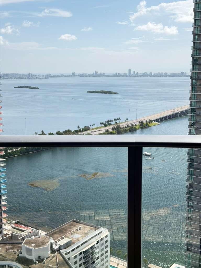 A high-angle view from a balcony overlooking a bay, a bridge, and distant city skyline — 501 NE 31st Street # 3804, Miami FL 33137, MIAMI, FL