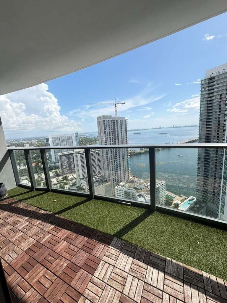 A balcony with wood deck tiles and artificial turf overlooks a city skyline and bay — 501 NE 31st Street # 3804, Miami FL 33137, MIAMI, FL