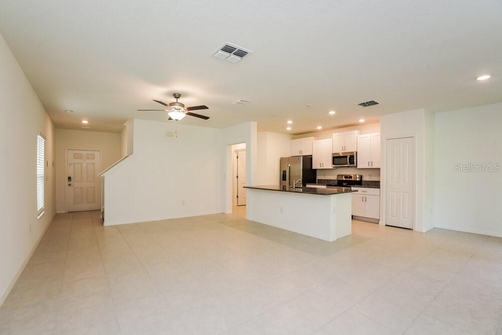 An open-concept kitchen and living area features tile flooring, white cabinetry, and a kitchen island — 7308 SPRING SNOWFLAKE AVENUE, TAMPA, FL