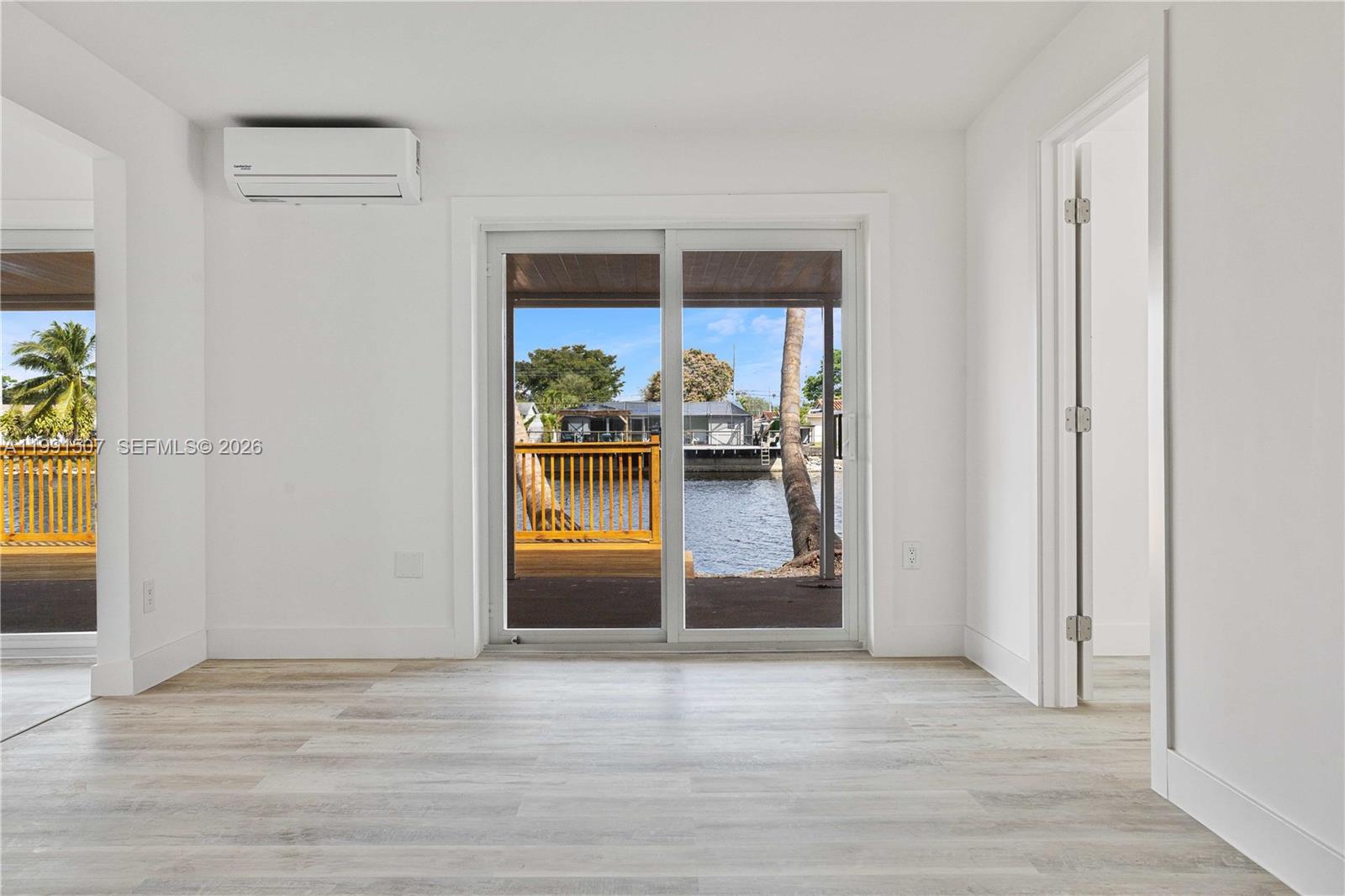 A bright room with white walls, light wood-look flooring, and sliding doors overlooking a canal — 4157 SW 49th Ct, Dania Beach FL 33314, DANIA BEACH, FL