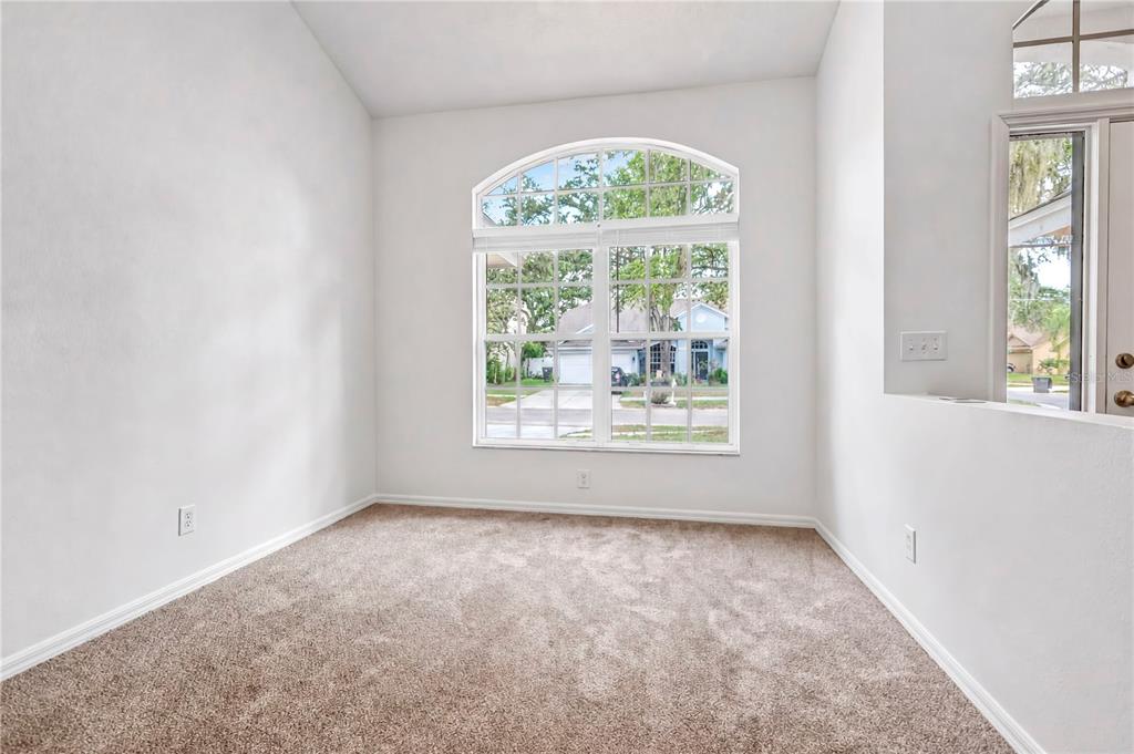 An empty room with beige carpet, white walls, and a large arched window — 2302 LYNCREST COURT, VALRICO, FL
