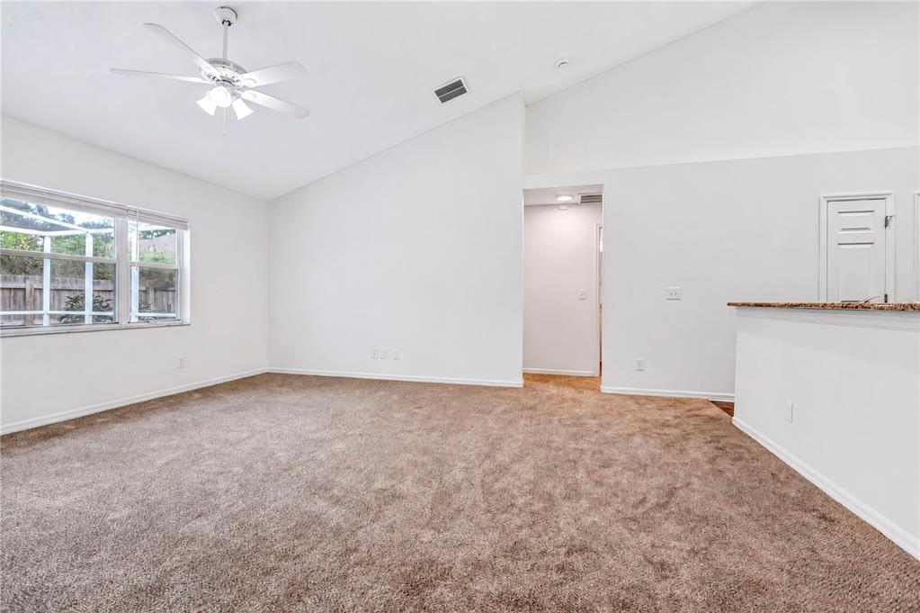 A spacious room with vaulted ceilings, beige carpeting, a ceiling fan, and a window — 2302 LYNCREST COURT, VALRICO, FL
