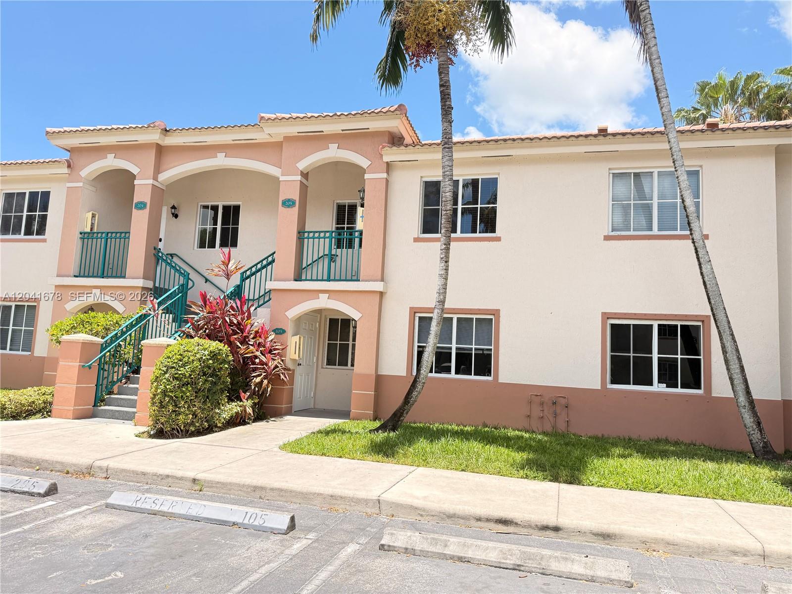 A two-story apartment building features beige stucco walls, teal railings, and a palm tree — 2930 SE 12th Rd # 31, Homestead FL 33035, HOMESTEAD, FL