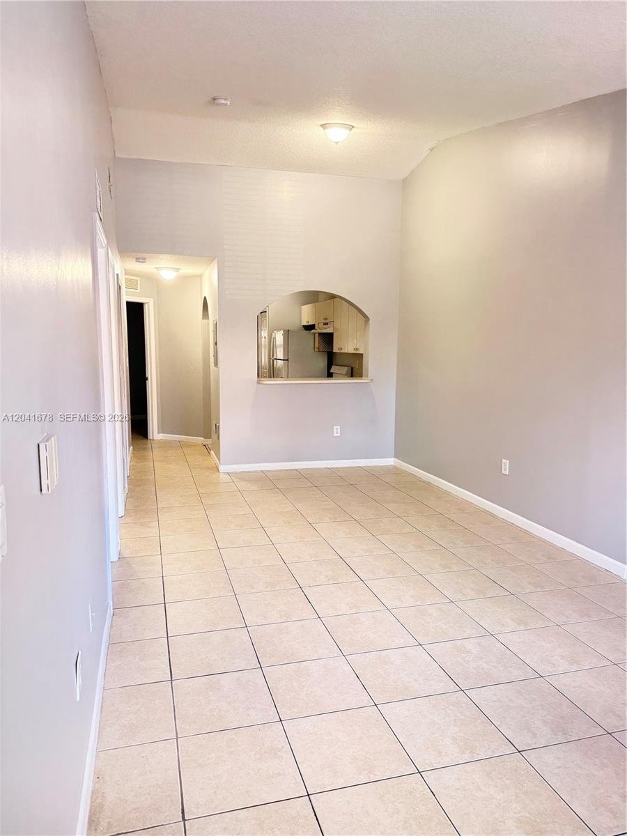 This room features light-colored tile flooring, gray walls, and an arched pass-through to the kitchen — 2930 SE 12th Rd # 31, Homestead FL 33035, HOMESTEAD, FL