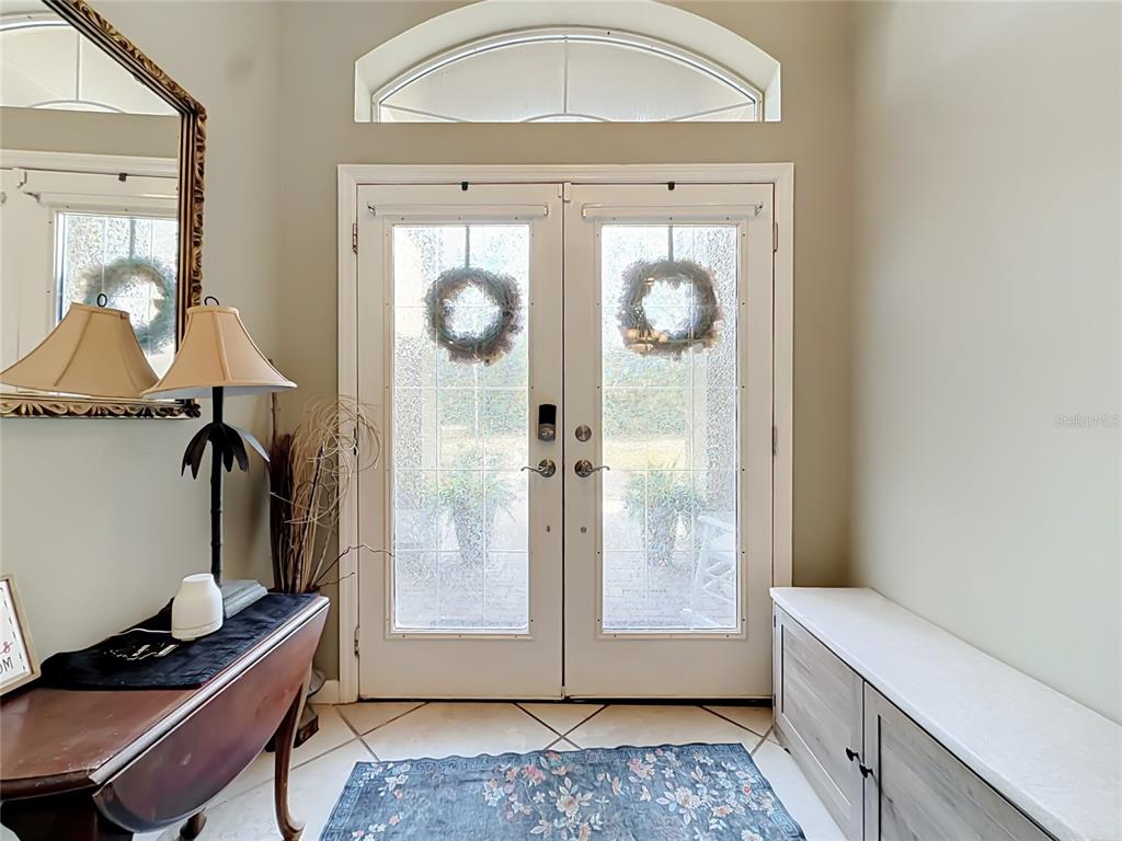 An entryway features double glass doors, a side table with a lamp, and a bench — 10301 FOX SPARROW AVENUE, WEEKI WACHEE, FL