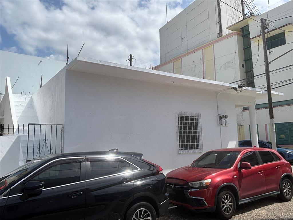 A white exterior building with a flat roof, external stairs, and two parked cars — 16 CELIS AGUILERA ST. CORNER, MANATI, PR