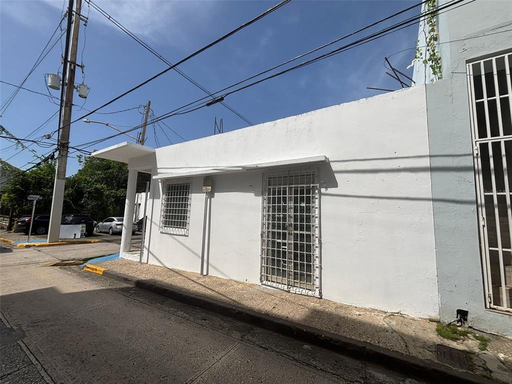 A white, single-story building with security bars on the windows and door sits on a street — 16 CELIS AGUILERA ST. CORNER, MANATI, PR