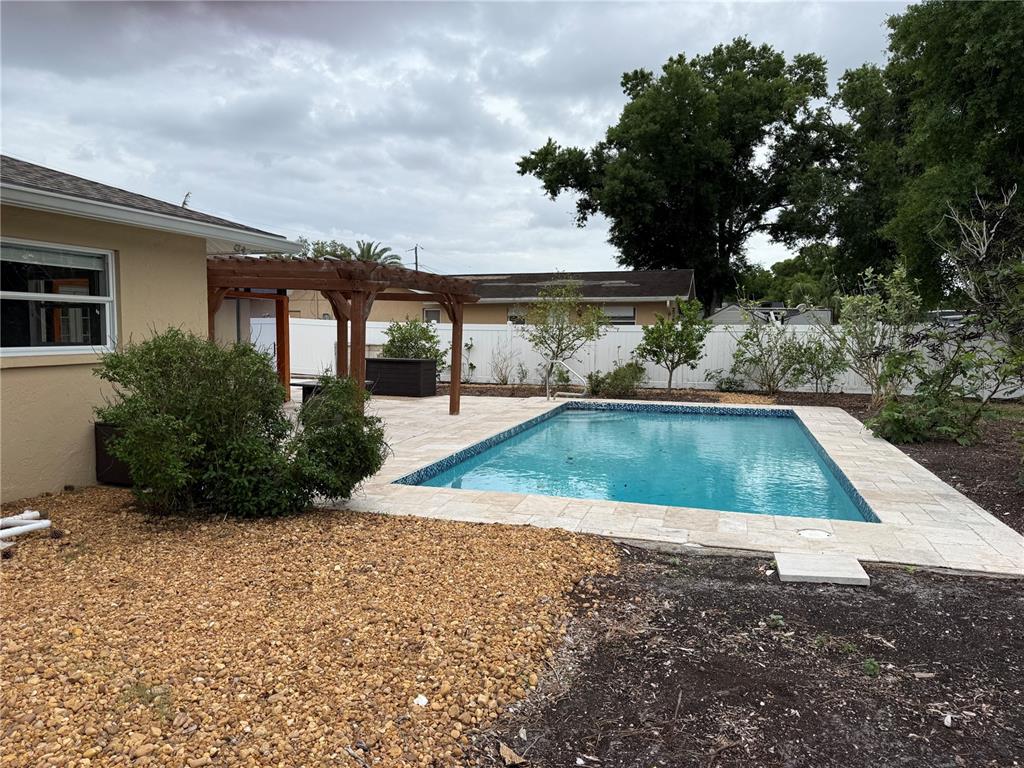 A backyard features a rectangular swimming pool, a wooden pergola, and a gravel ground cover — 98 DADE AVENUE, SARASOTA, FL