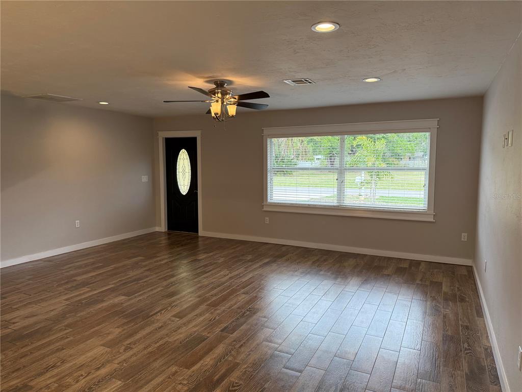 A living room with wood-look tile flooring, a ceiling fan, and a large window — 98 DADE AVENUE, SARASOTA, FL