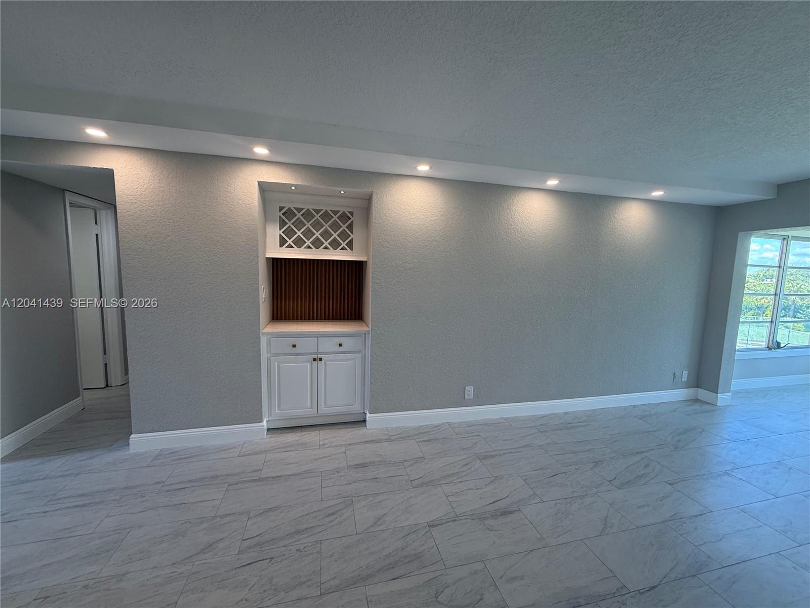 A room with gray walls, marble-look tile flooring, and a built-in white bar cabinet — 9273 SW 8th St # 311, Boca Raton FL 33428, BOCA RATON, FL