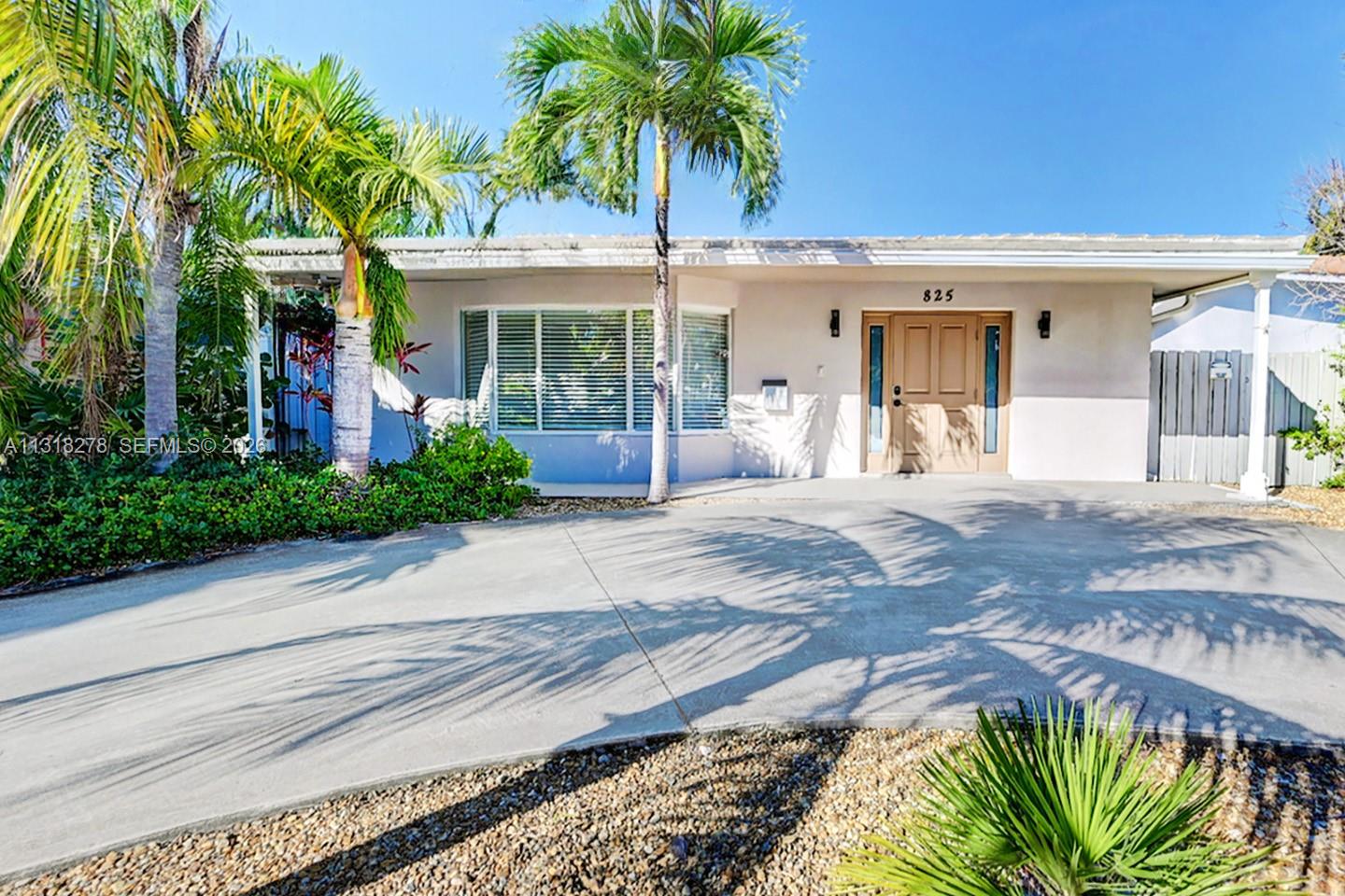 A single-story house with a concrete driveway, palm trees, and a light-colored exterior — 825 Harrison St, Hollywood FL 33019, HOLLYWOOD, FL
