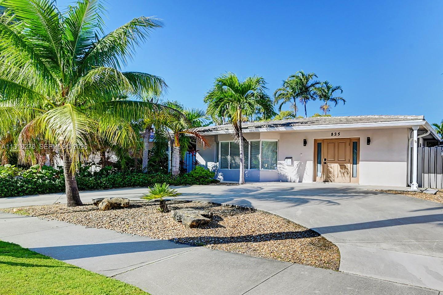 A single-story house with a concrete driveway, palm trees, and a gravel landscaping bed — 825 Harrison St, Hollywood FL 33019, HOLLYWOOD, FL