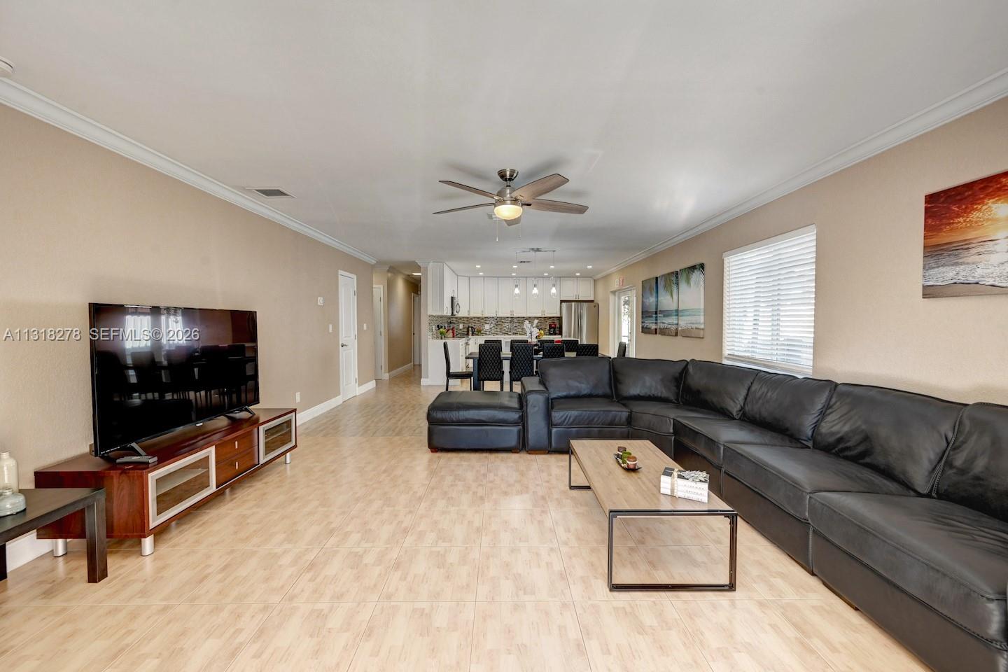 A living room with tile floors, a black sectional sofa, and an open kitchen area — 825 Harrison St, Hollywood FL 33019, HOLLYWOOD, FL