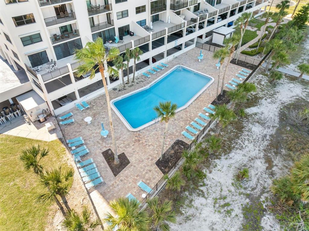 An aerial view shows a rectangular swimming pool surrounded by lounge chairs and palm trees — 1270 GULF BOULEVARD UNIT 606, CLEARWATER BEACH, FL