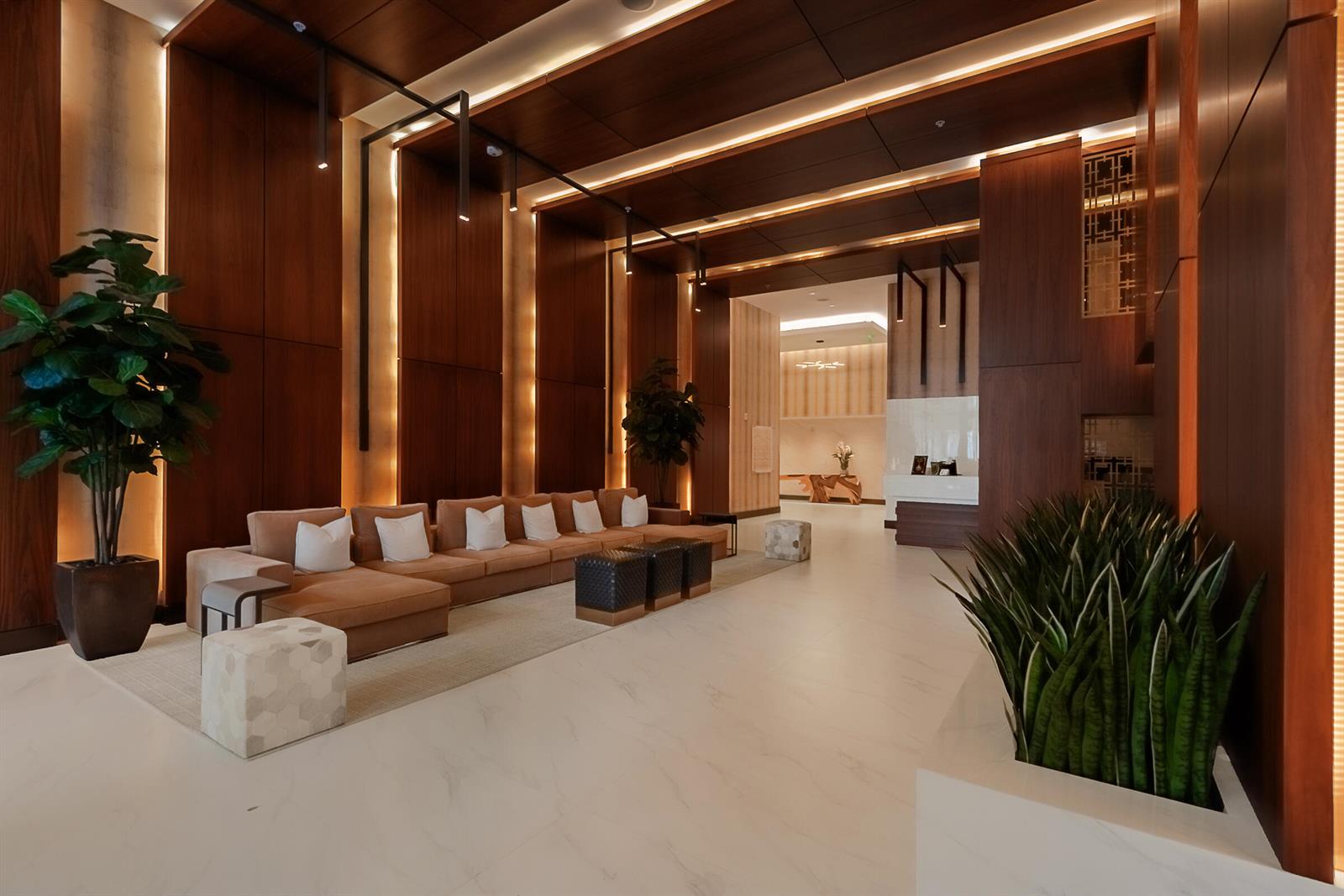 A modern hotel lobby features wood-paneled walls, a long tan sofa, and white marble floors — 2960 NE 207th Street # 708, Aventura FL 33180, AVENTURA, FL