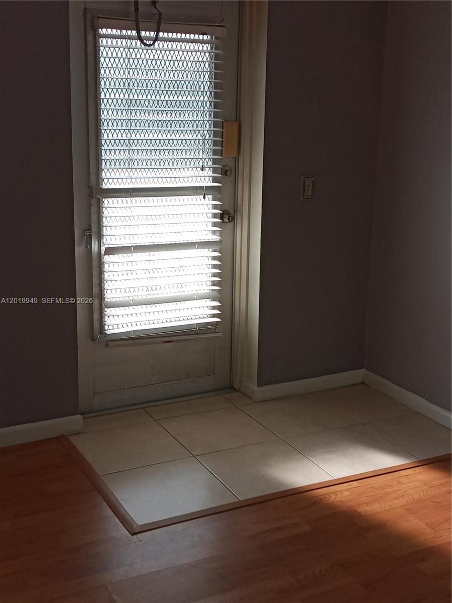 A door with horizontal blinds leads to a tiled entryway next to wood-look flooring — 390 Windsor Q # 390, West Palm Beach FL 33417, WEST PALM BEACH, FL