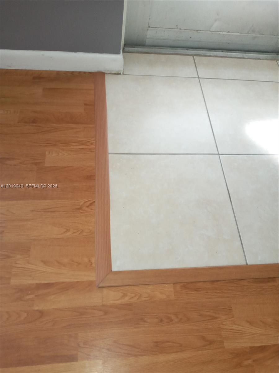 This image shows a transition between wood-look laminate flooring and light-colored square floor tiles — 390 Windsor Q # 390, West Palm Beach FL 33417, WEST PALM BEACH, FL
