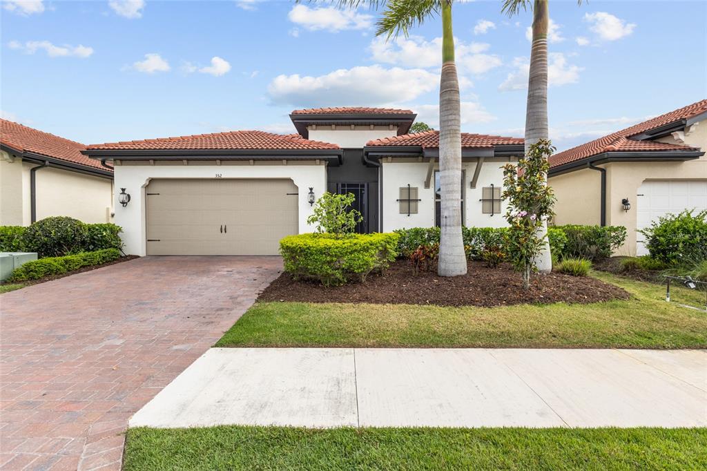 A single-story house with a tan garage, white stucco walls, and two tall palm trees — 352 TOSCAVILLA BOULEVARD, NOKOMIS, FL