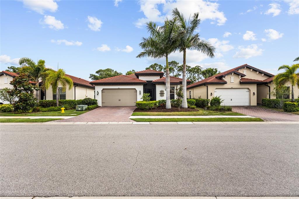 A single-story house with a tiled roof, two-car garage, and palm trees in the front — 352 TOSCAVILLA BOULEVARD, NOKOMIS, FL