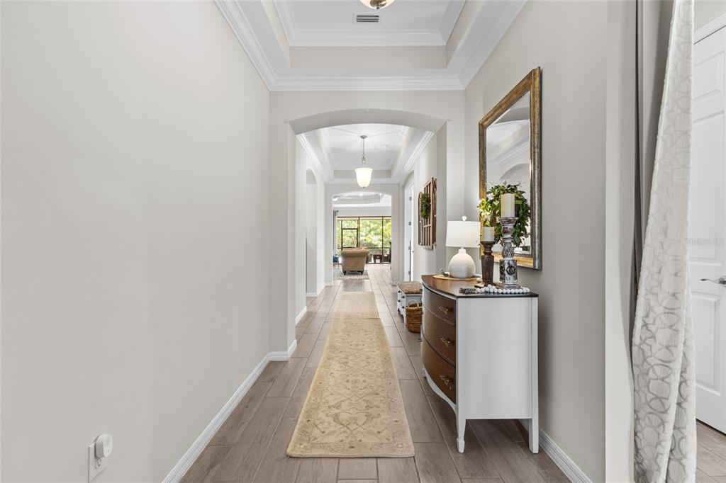 A hallway with wood-look tile flooring, a runner rug, and a console table with a mirror — 352 TOSCAVILLA BOULEVARD, NOKOMIS, FL