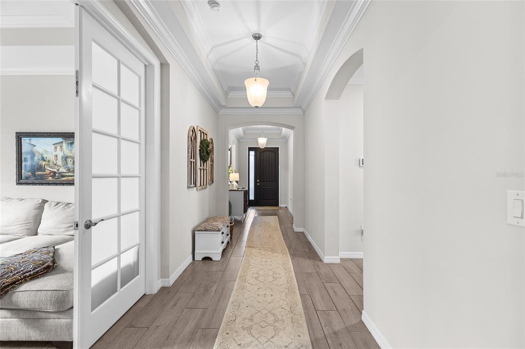 A long hallway with wood-look tile floors leads to a dark front door — 352 TOSCAVILLA BOULEVARD, NOKOMIS, FL