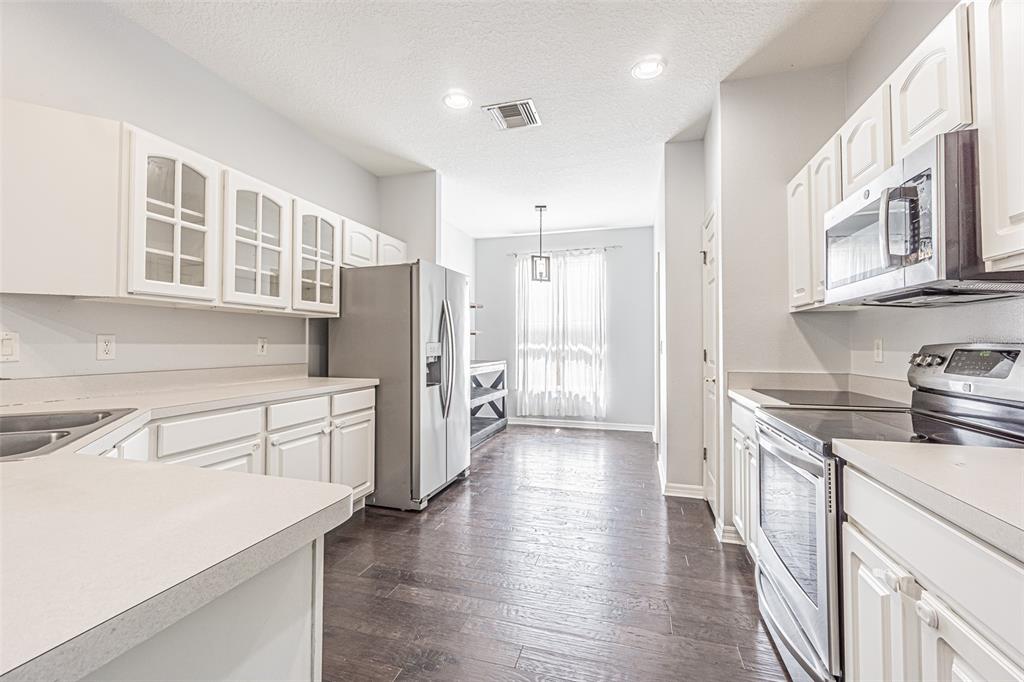 A kitchen with white cabinets, stainless steel appliances, and dark wood flooring — 19145 WOOD SAGE DRIVE, TAMPA, FL