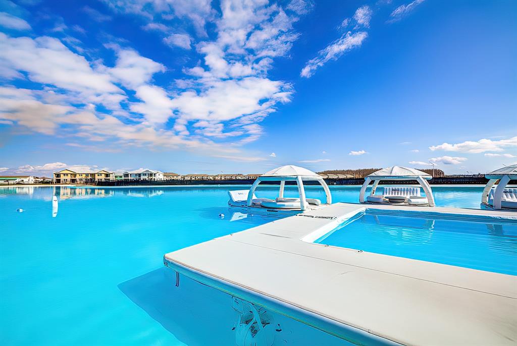 A bright blue lagoon features floating cabanas and a white platform in the foreground — 31604 BLUE PASSING LOOP, WESLEY CHAPEL, FL