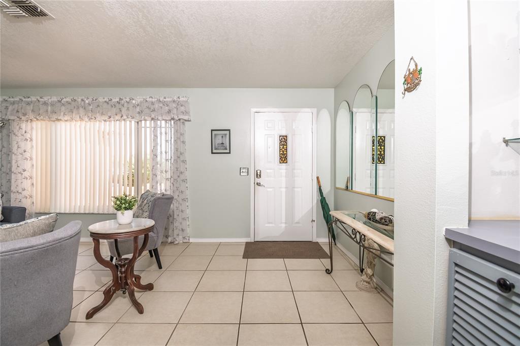 An entryway features tiled floors, a white front door, and a console table with mirrors — 7812 TURNBRIDGE DRIVE, PORT RICHEY, FL