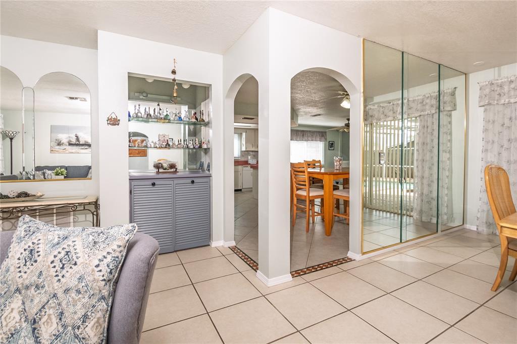 A living and dining area featuring arched doorways, tiled floors, and a mirrored wall — 7812 TURNBRIDGE DRIVE, PORT RICHEY, FL