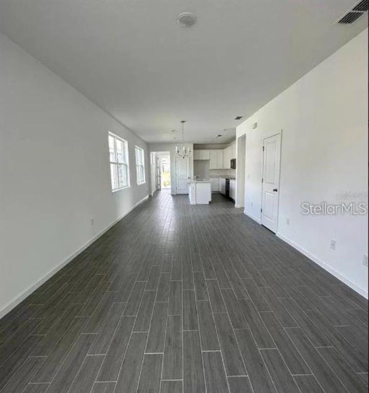 An open-concept living and kitchen area features gray wood-look tile flooring and white walls — 4350 DAVOS DRIVE, CLERMONT, FL