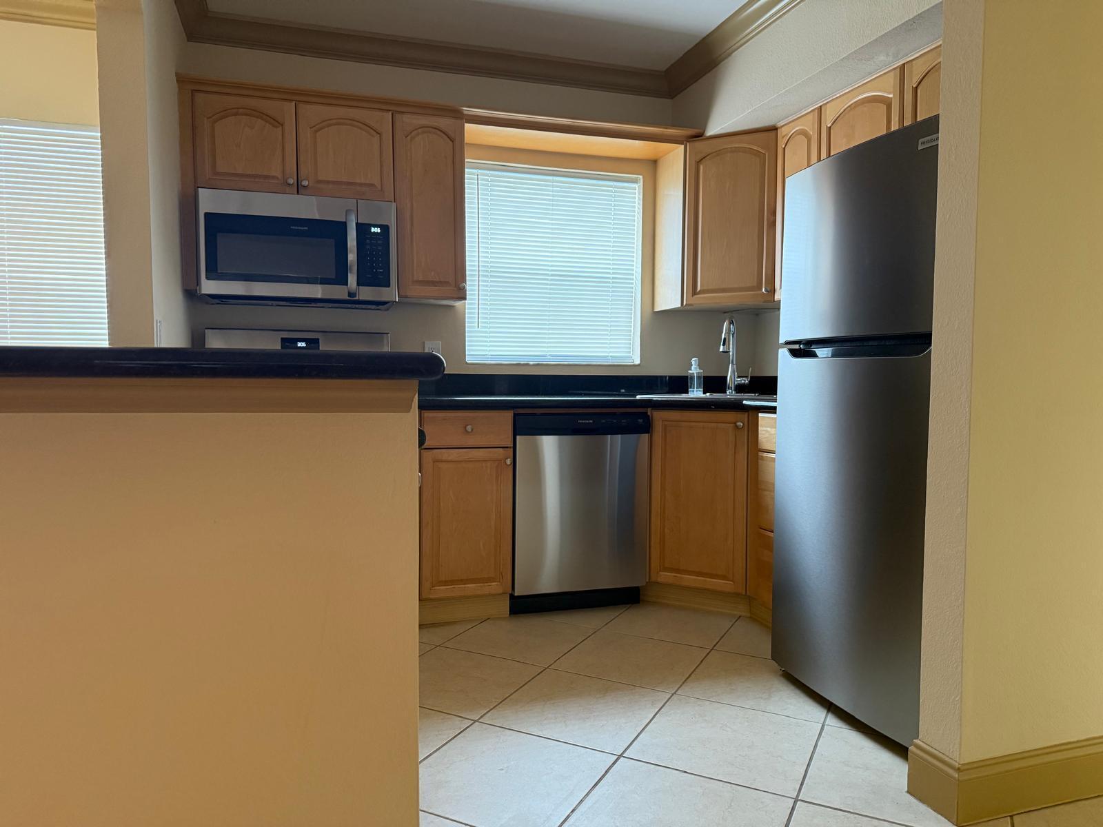 A kitchen with light wood cabinets, stainless steel appliances, black countertops, and tile flooring — 744 NE 14th Avenue # 12, Fort Lauderdale FL 33304, FORT LAUDERDALE, FL