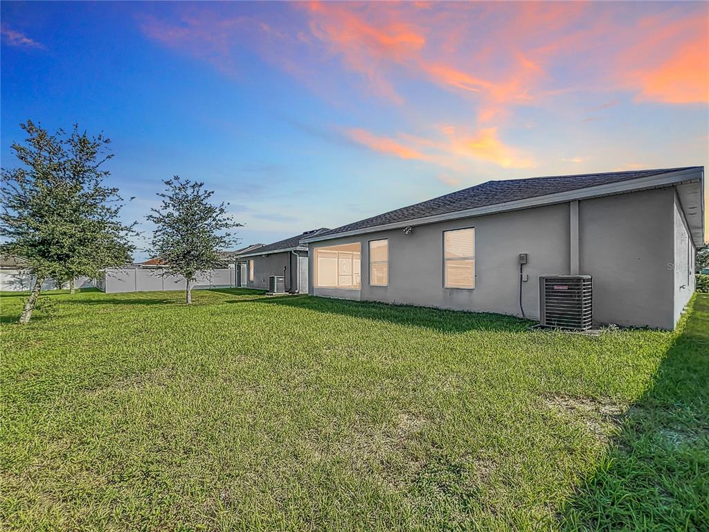 The exterior of a single-story house features a screened-in porch and a backyard lawn — 653 PERSIAN DRIVE, HAINES CITY, FL