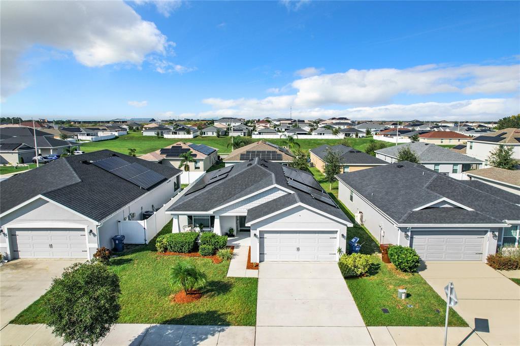 An aerial view of a suburban neighborhood featuring houses with solar panels on their roofs — 653 PERSIAN DRIVE, HAINES CITY, FL