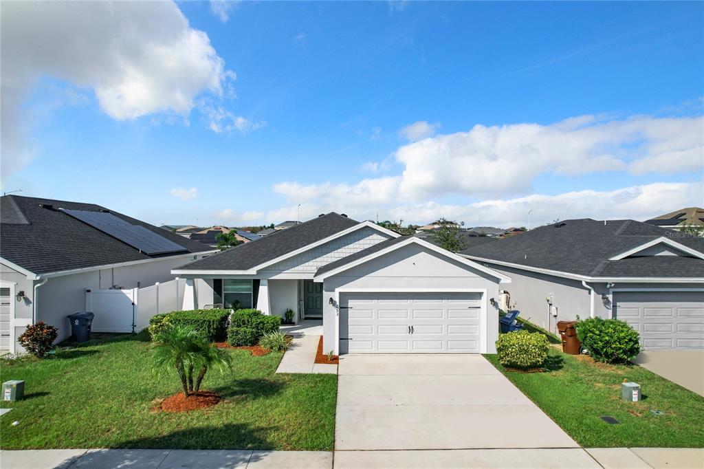 A single-story suburban house with a gray exterior, a two-car garage, and a front lawn — 653 PERSIAN DRIVE, HAINES CITY, FL