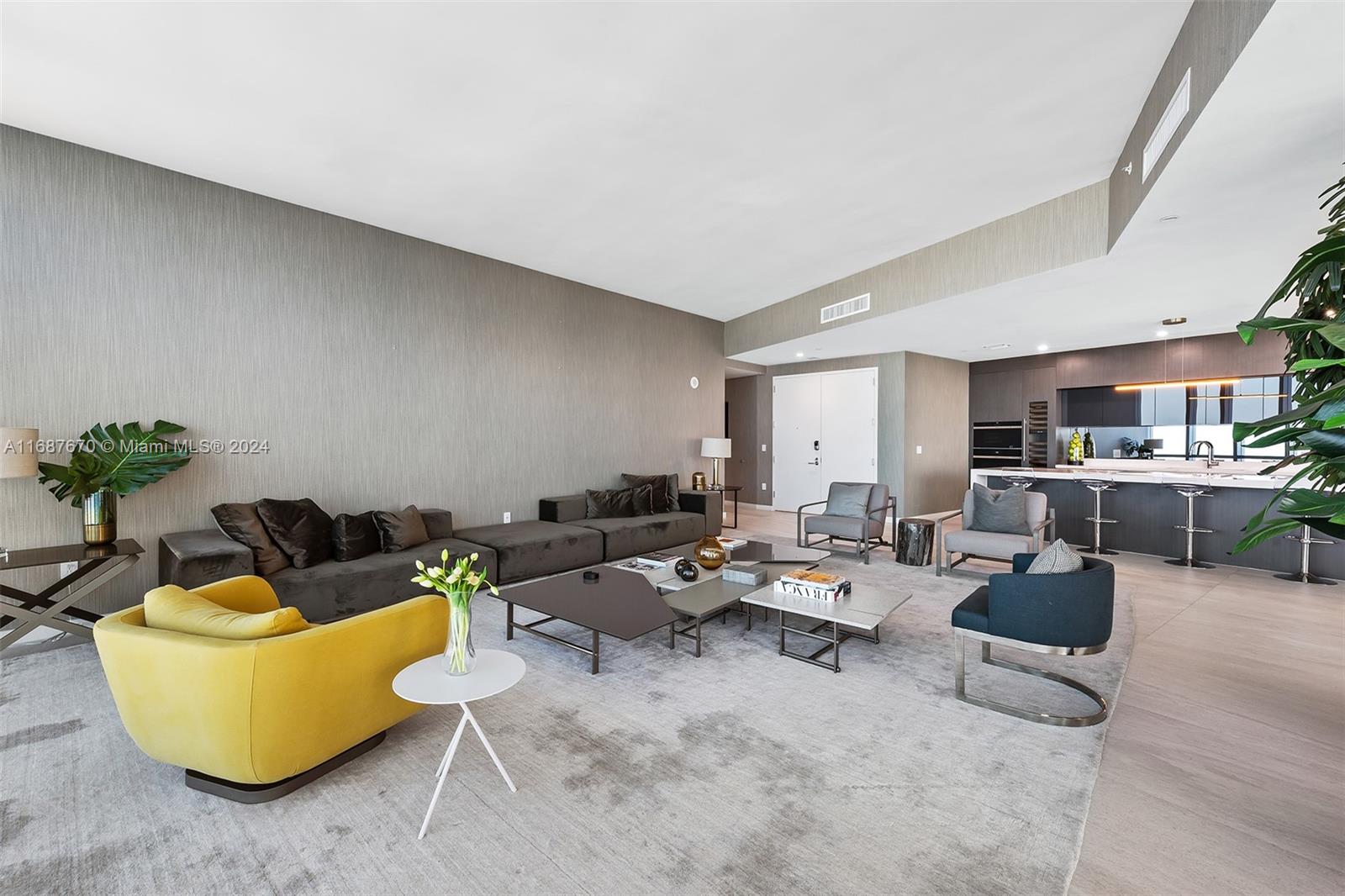 A modern open-concept living room features a large gray sectional, yellow armchair, and kitchen island — 851 NE 1st Ave # 5112, Miami FL 33132, MIAMI, FL