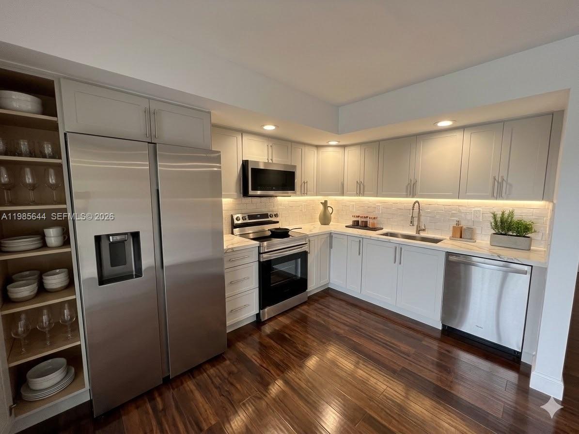 A kitchen features light gray cabinets, stainless steel appliances, white subway tile, and dark wood flooring — 8635 NW 8th St # 211, Miami FL 33126, MIAMI, FL