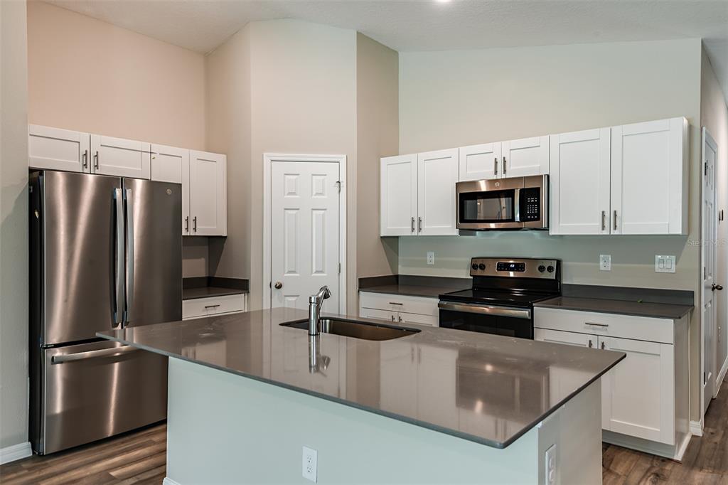 A kitchen features white cabinets, stainless steel appliances, and a large island with a sink — 4531 WYNNSTONE DRIVE, DAVENPORT, FL