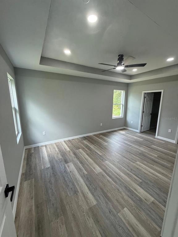 A bedroom features gray walls, wood-look flooring, a tray ceiling with recessed lighting, and a fan — 1627 PICKEREL COURT, POINCIANA, FL