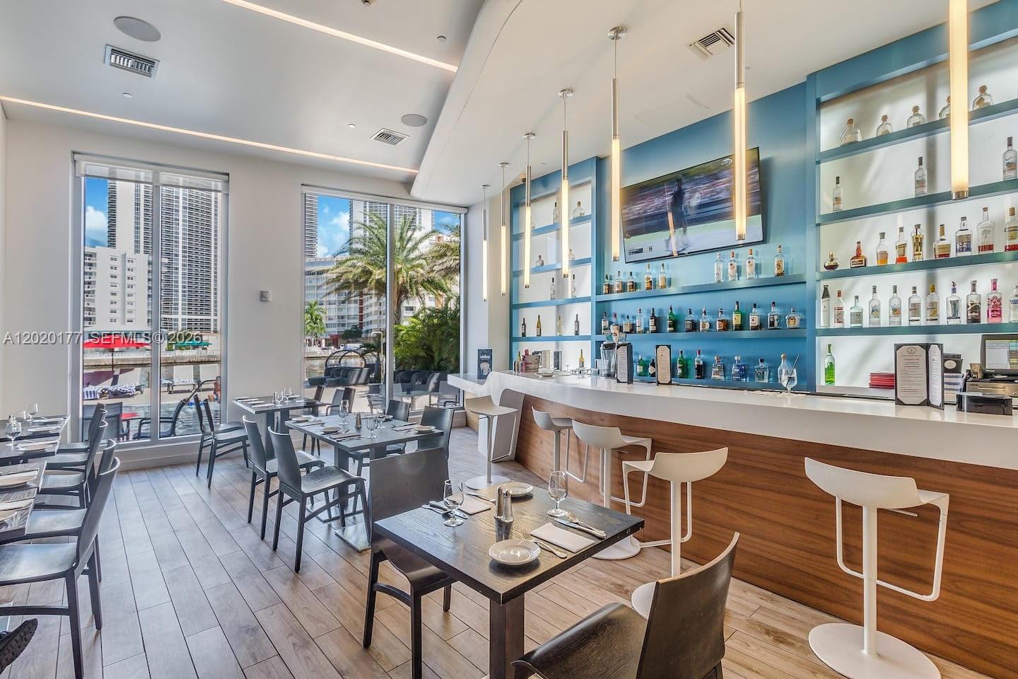 A modern bar and dining area features a white counter, wooden base, and floor-to-ceiling windows — 2602 E Hallandale Beach Blvd # R2604, Hallandale Beach FL 33009, HALLANDALE BEACH, FL