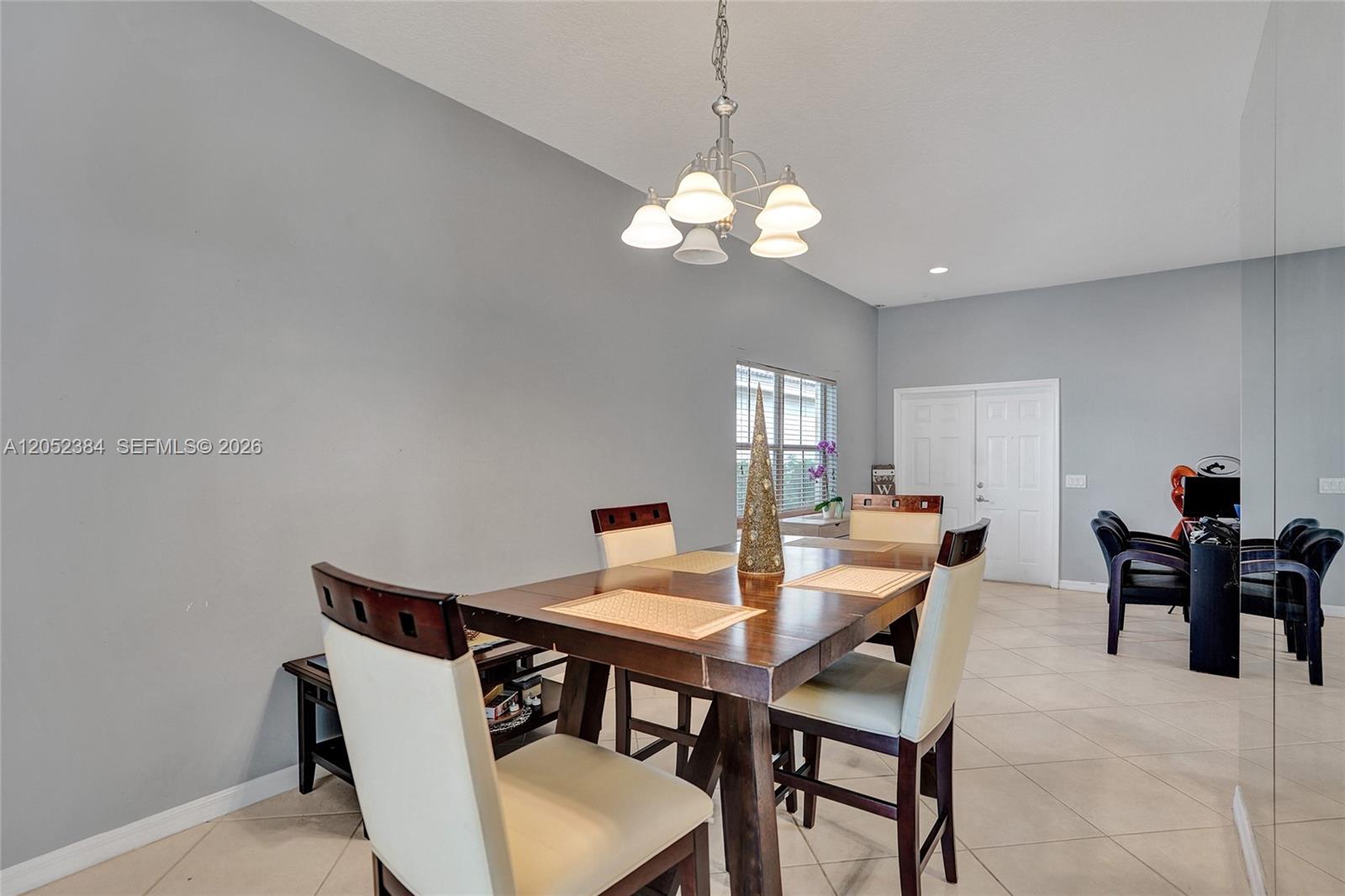 A dining room features a wooden table, four chairs, and a chandelier on tile flooring — 4219 Sabal Ridge Cir, Weston FL 33331, WESTON, FL