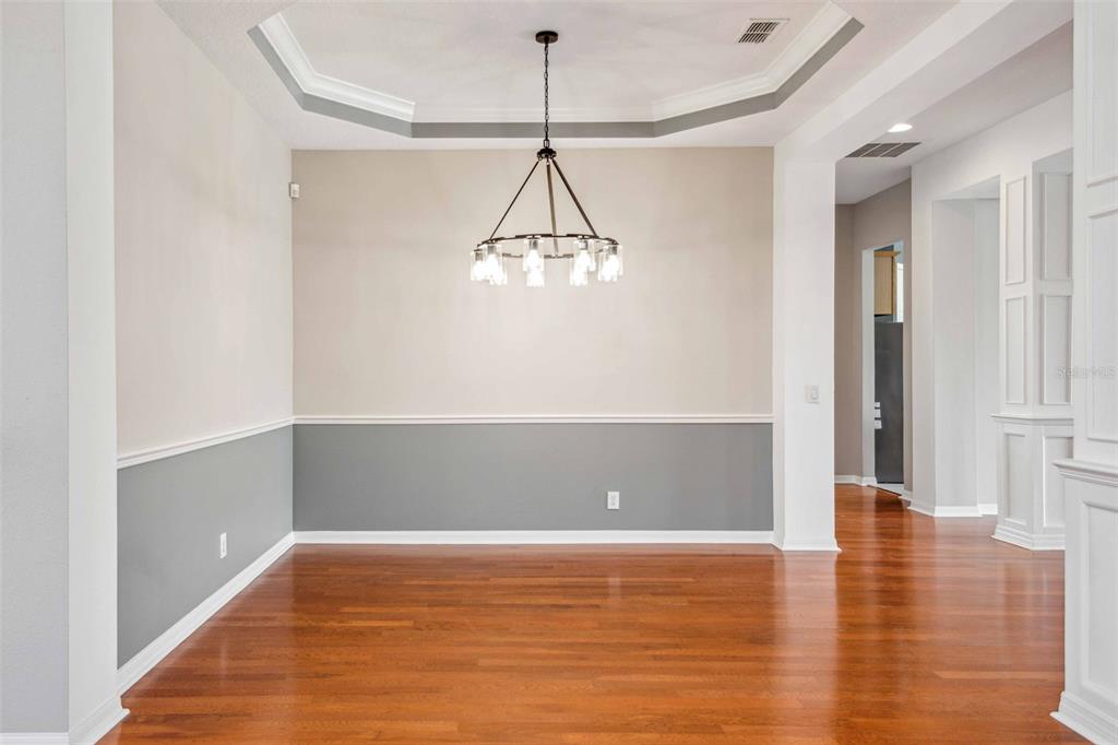 A dining room with hardwood floors, a tray ceiling, and two-toned gray and beige walls — 10226 DEERCLIFF DRIVE, TAMPA, FL