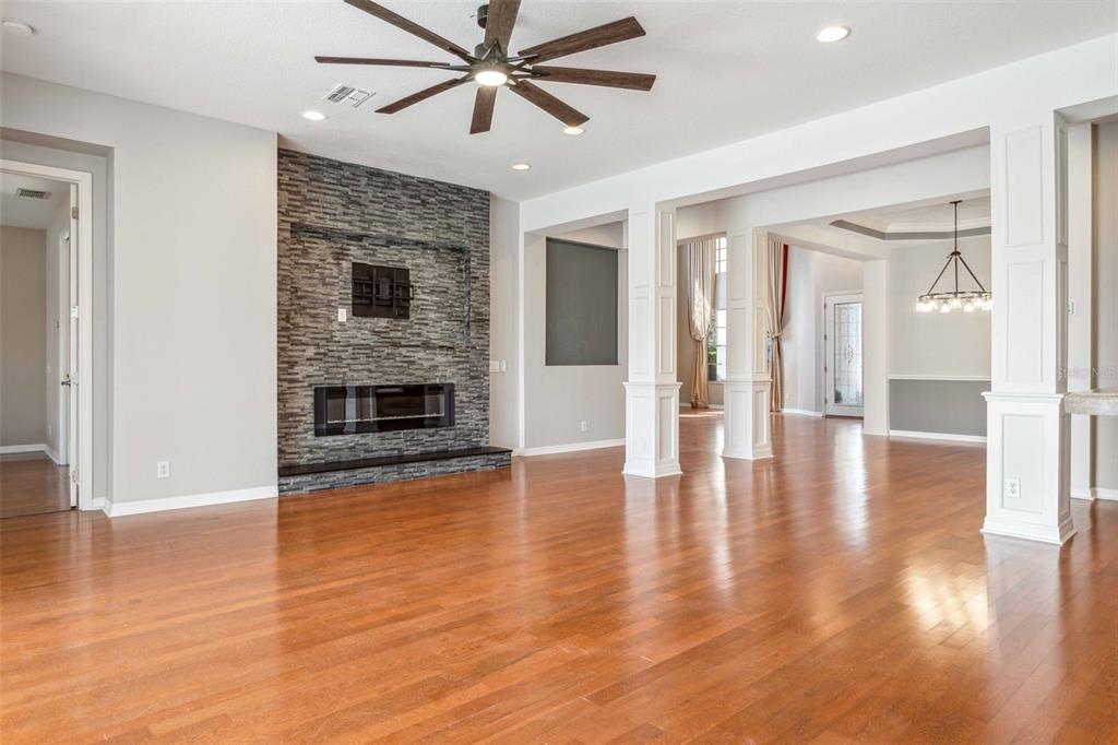 A spacious living room features hardwood floors, a stone fireplace, and a ceiling fan — 10226 DEERCLIFF DRIVE, TAMPA, FL