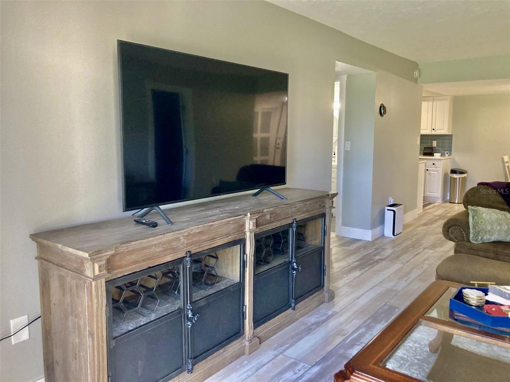 A living room features a large television on a wooden media console with metal doors — 6114 43RD STREET W UNIT 103E, BRADENTON, FL