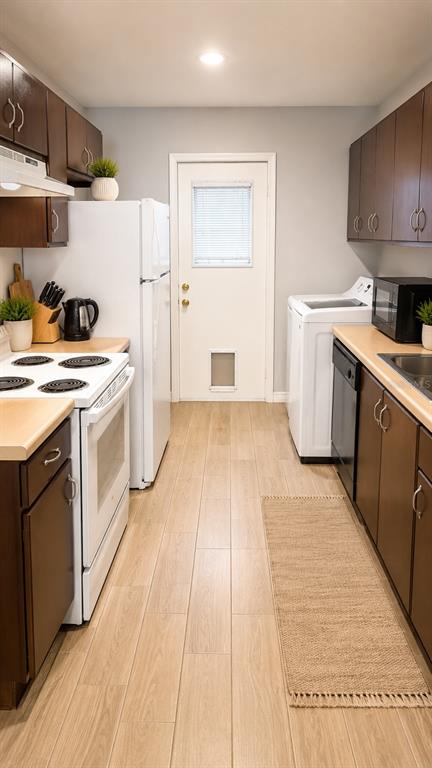 A galley-style kitchen features dark wood cabinets, white appliances, and light wood-look tile flooring — 245 WINTER RIDGE BOULEVARD, WINTER HAVEN, FL