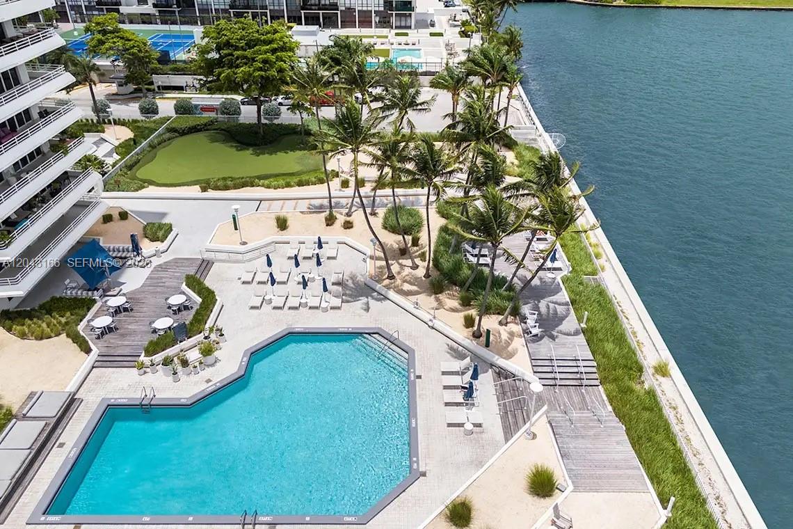 An aerial view shows a swimming pool, lounge chairs, palm trees, and a waterfront deck — 555 NE 34th St # 1102, Miami FL 33137, MIAMI, FL