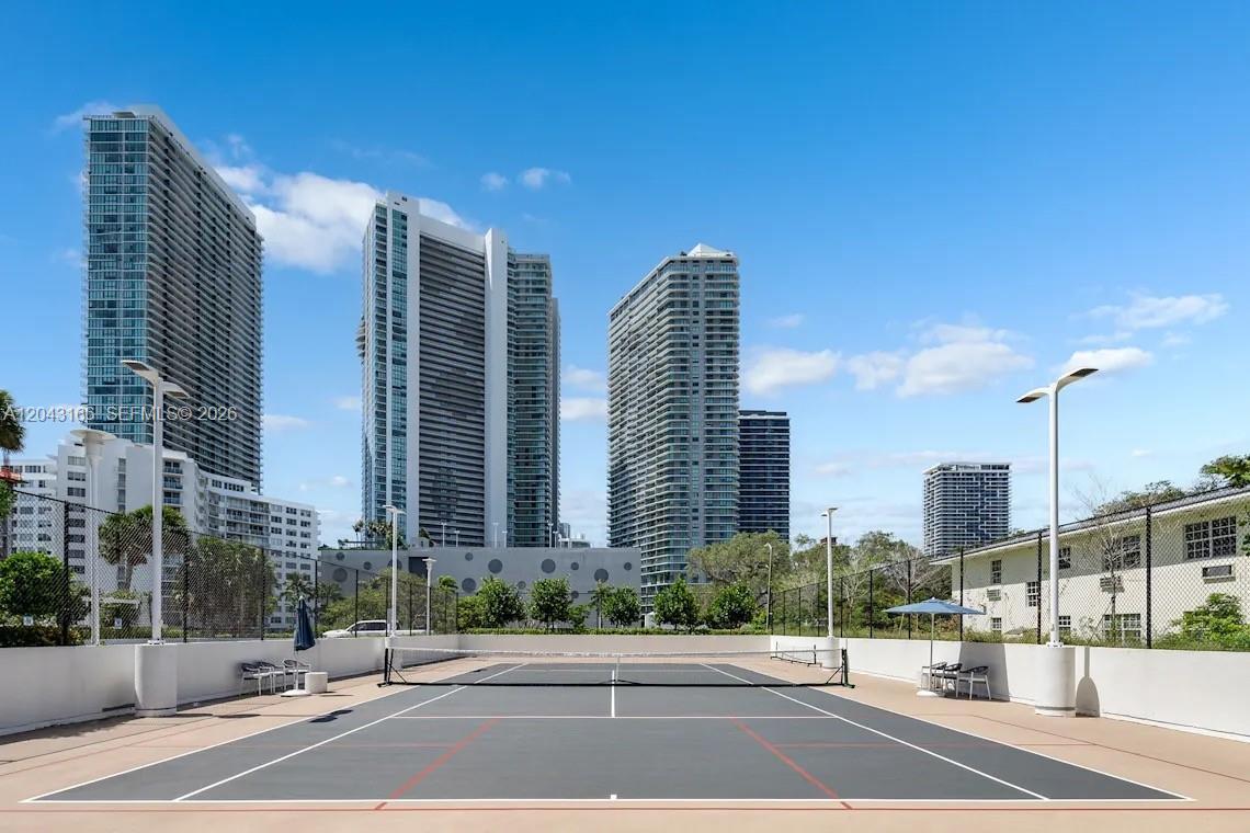 A tennis court with a net is situated in front of several high-rise buildings — 555 NE 34th St # 1102, Miami FL 33137, MIAMI, FL
