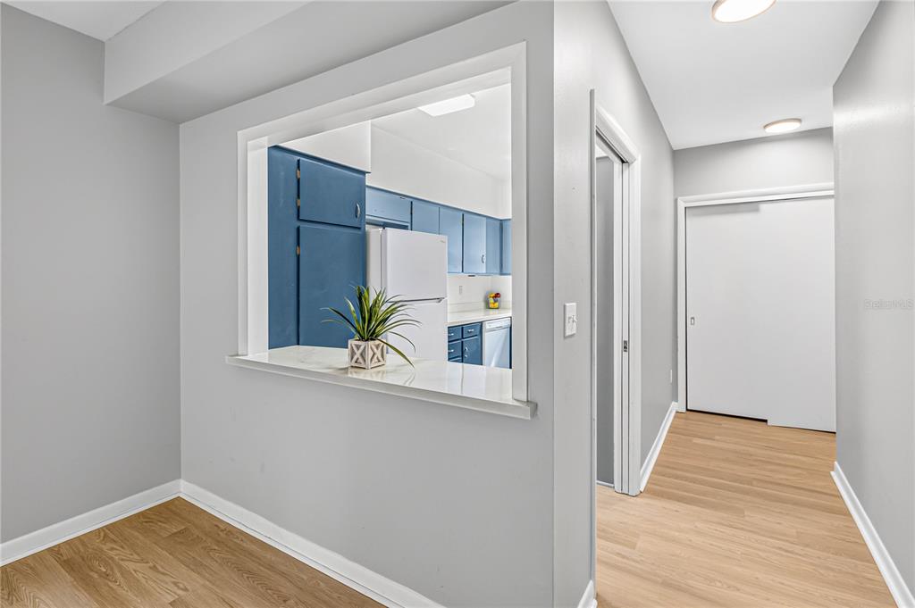 A view from a room looking through a pass-through window into a blue-cabinet kitchen — 223 WINDSOR STREET UNIT 4, LAKELAND, FL