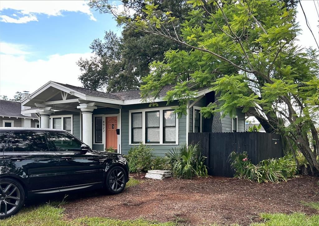 A green bungalow with a front porch and a black SUV parked in the driveway — 4922 N SUWANEE AVENUE, TAMPA, FL