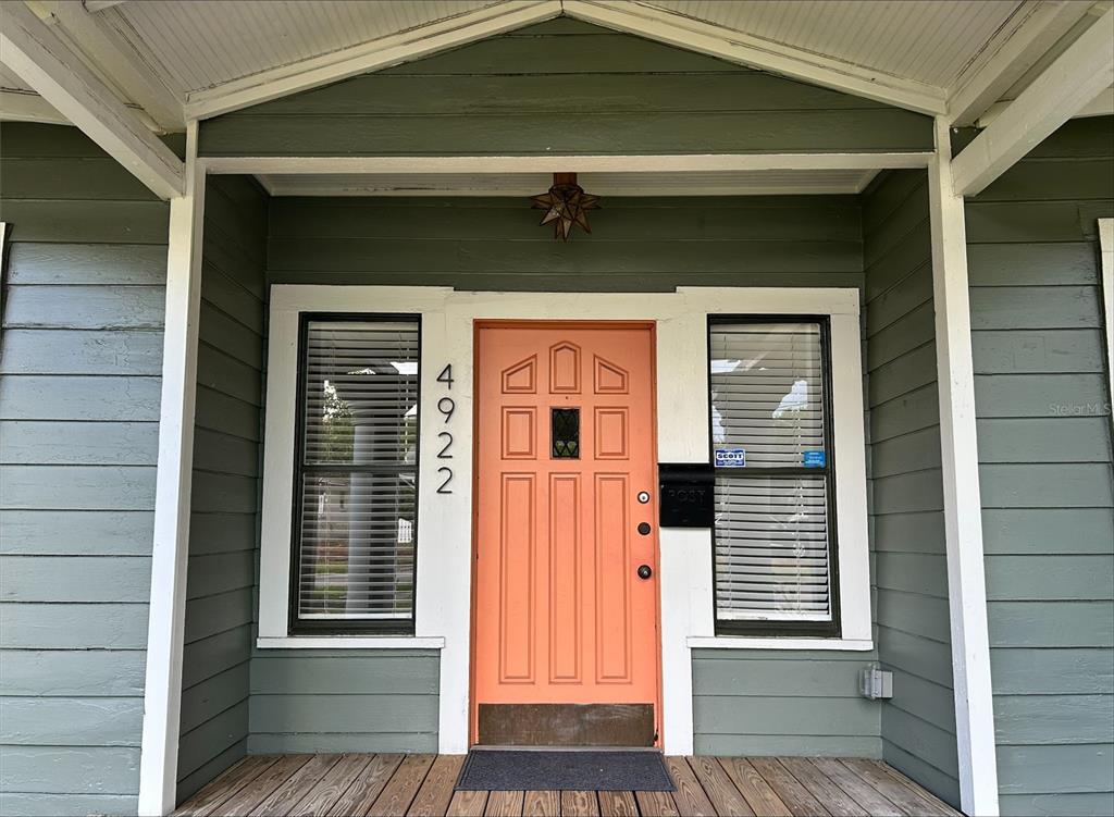 A front porch features a coral-colored door with vertical house numbers and two flanking windows — 4922 N SUWANEE AVENUE, TAMPA, FL